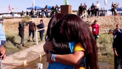 Two relatives hugging at the Mexico-US border.