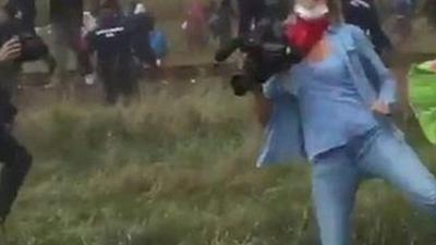 A Hungarian camerawoman apears to kick a migrant