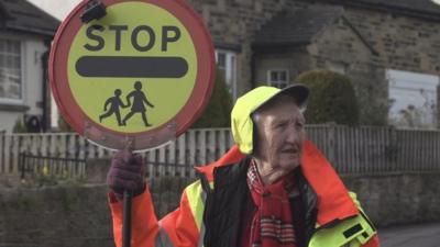 Lollipop lady holding up a Stop sign