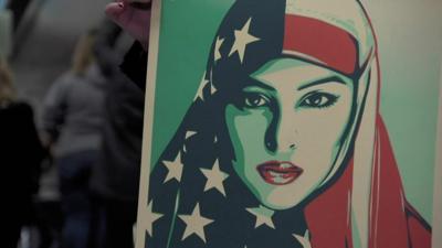 Demonstrators holds a placard showing a woman wearing a veil with the US flag