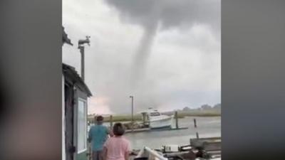 People stand on a dock, looking at the waterspout