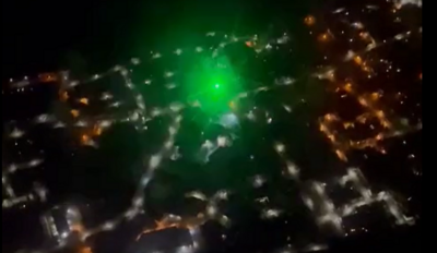 A green laser shining amongst others lights on the ground