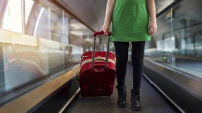 Woman with suitcase on moving airport walkway