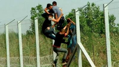 Young men climb over the border fence dividing Serbia and Hungary to enter the EU.
