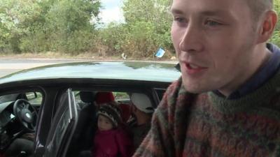 British PhD student Oliver with a Syrian family inside a car in the background