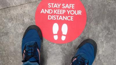 sign-on-floor-saying-stay-safe-and-keep-your-distance