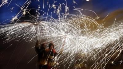 Revellers hold fireworks as they take part in Correfoc