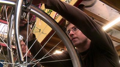 Mike, who was helped by a social start-up, fixes a bicycle
