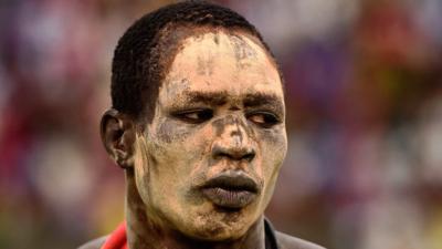 A wrestler with white ash smeared on his face