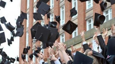 Graduates throw their mortar boards into the air