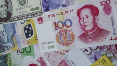 Selection of notes of different currencies with a Chinese note on top