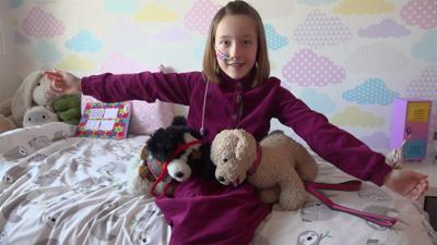 Imogen sitting on her bed with stuffed animals