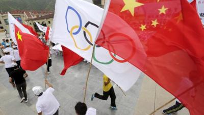 People waving Chinese and Olympics flags