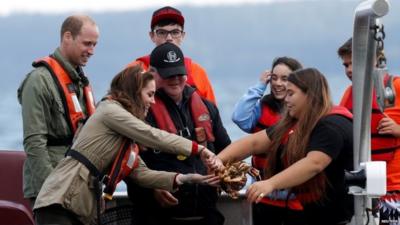 The Duchess of Cambridge handles a crab pulled from a trap in the water while fishing with Prince William during a visit to Haida Gwaii, Canada