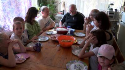 Children and adults sitting around a table about to eat lunch