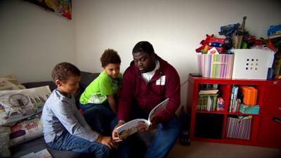 Suhmayah reading to his two chilren