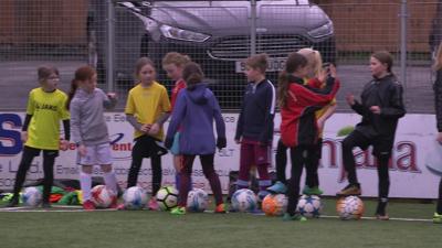 Row of girls with footballs