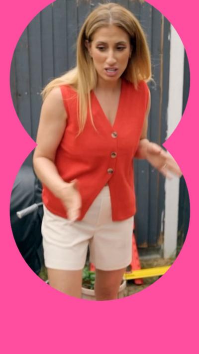 A woman in an orange vest and cream shorts stands in a garden