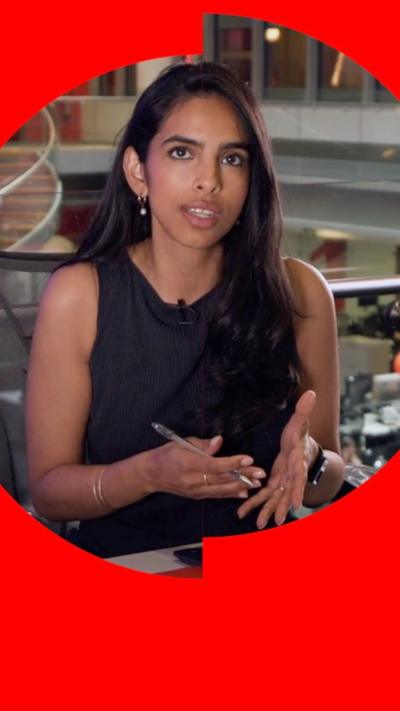 BBC Verify correspondent Merlyn Thomas with long dark hair at an office desk