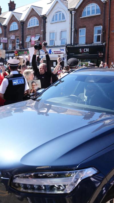 A car carrying Keir Starmer drives with protesters either side