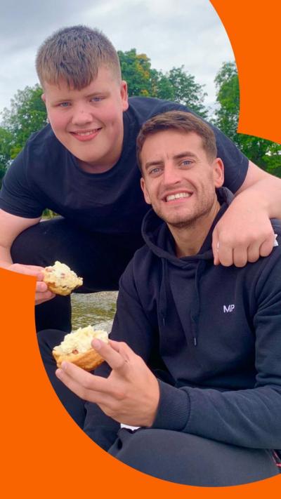 Josh McDonald wears a blue hoody and smiles at the camera. His younger brother Max wears a blue T-shirt and crouches beside Josh and puts his arm around him.