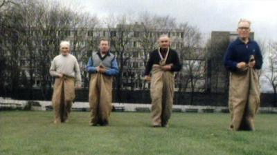 Four men taking part in a sack race.