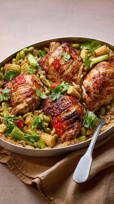 Four chicken pieces surrounded by vegetables in a Thai green sauce on light coloured plate.