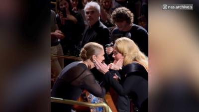 Adele and Celine Dion holding each other's faces in their hands