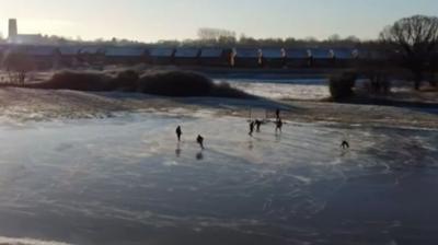 Members of the team playing on the ice. Howden Minster can be seen in the background