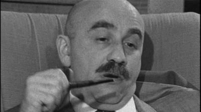 Warren Mitchell smoking a pipe