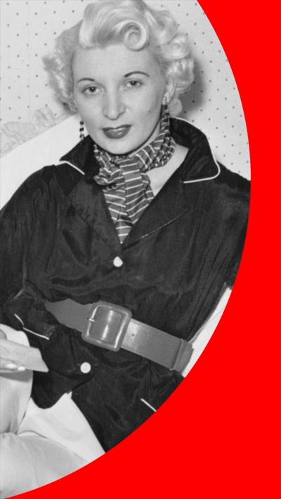 A black and white photo of Ruth Ellis. She has curly blonde hair and is wearing a dark coloured jacket and a striped scarf.