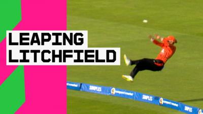 Phoebe Litchfield leaps backwards while pushing the ball away to ensure that it doesn't fly over the boundary