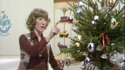 Lesley Judd sits beside a Christmas tree with egg box decorations on it