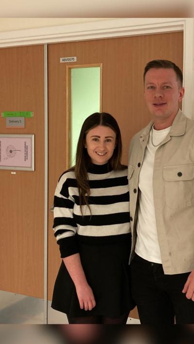 A woman in a black and white horizontally striped jumper with a man in a beige jacket with white t-shirt