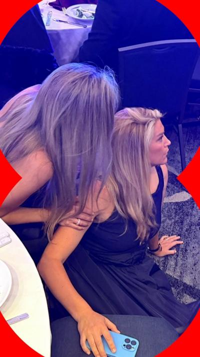 Two women crouched on the floor behind a tablet