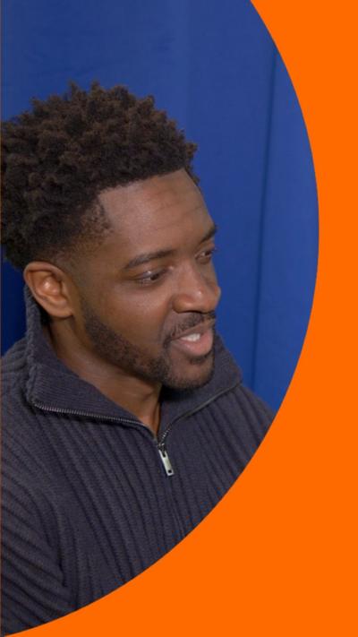 A man with short black hair wearing a blue jumper