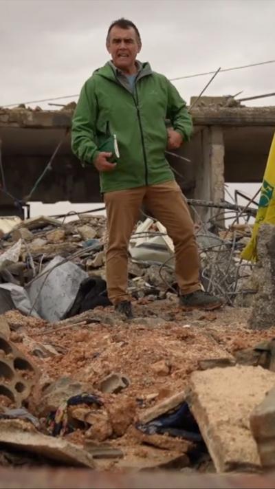 The BBC's Wyre Davies standing on a pile of rubble