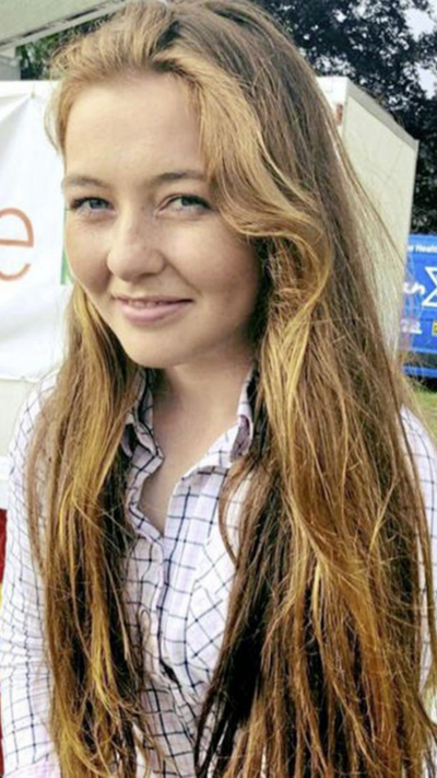 A woman with long brown hair wearing a white shirt.