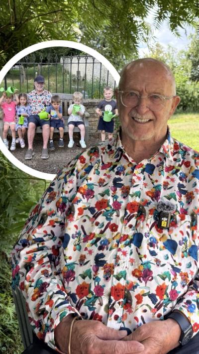 Walter Minns in a flower patterned shirt sitting with children on a bench