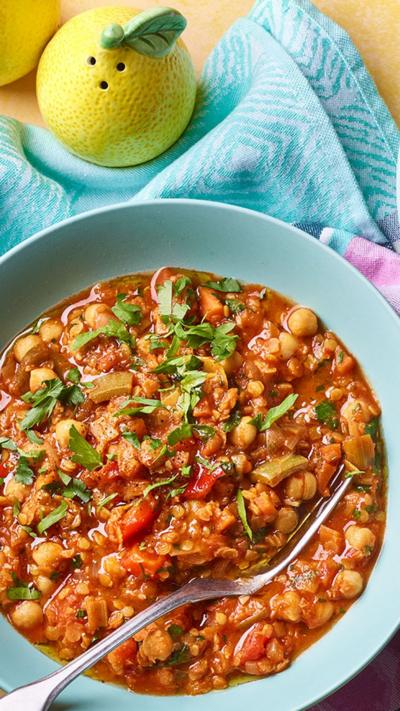 Two blue bowls containing harissa stew sit on a brightly coloured napkin.