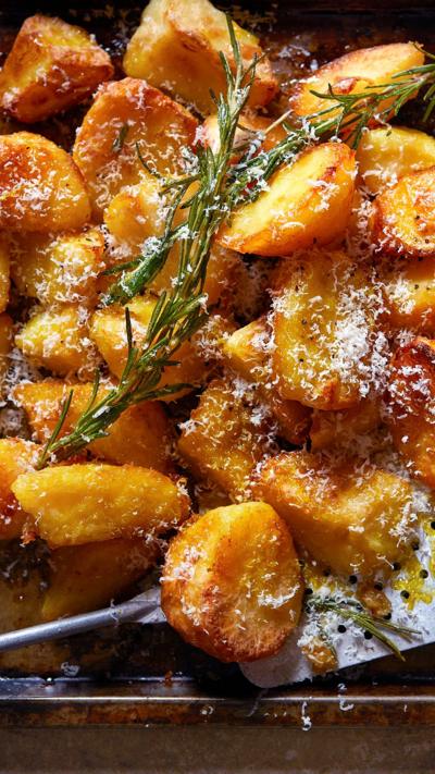 Top down video of roast potatoes in a baking tray covered with parmesan and sprigs of rosemary
