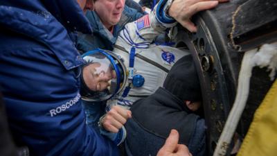 NASA astronaut Jonny Kim receives assistance from specialists while getting out of the Soyuz MS-27 space capsule