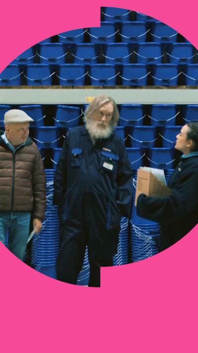 Two men and a woman stand in front of a wall full of blue buckets.