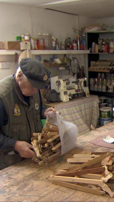 Man wearing Army gear at a workshop with lots of wood in front of him.