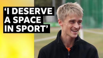 Athlete Seamus Derbyshire smiling whilst sitting down at an athletics track. He is wearing a black jumper. The words next to him are: "I deserve a space in sport".