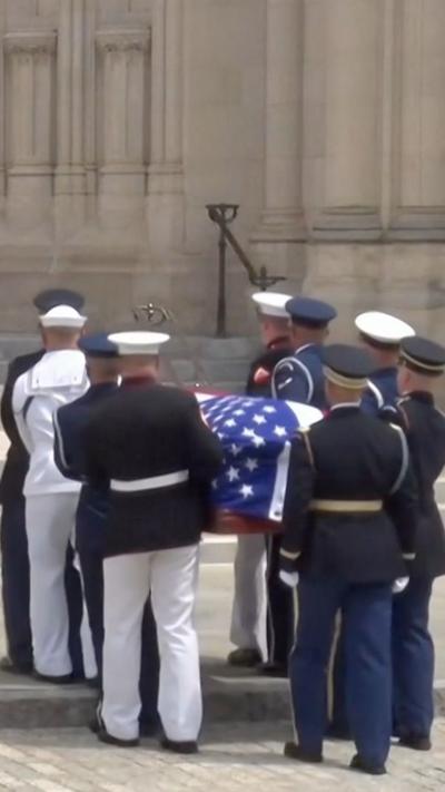 Service members hold a casket draped in the US flag into the National Cathedral, Washington DC.
