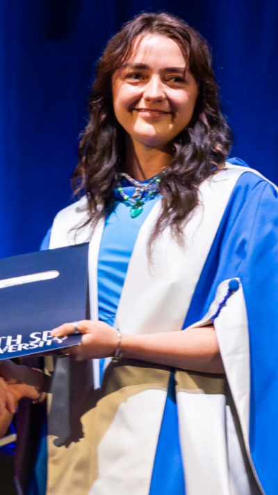 Maisie, who wears a blue dress and a white gown, collects an honorary degree