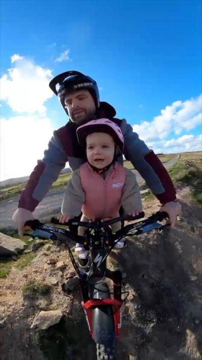 A dad and daughter on a bike in helmets