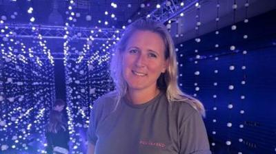 A woman stood in a dark room amongst hundreds of blue lights