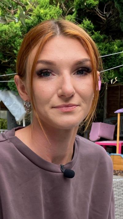 a red headed woman sat in a garden wearing a purple top